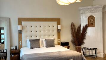A modern bedroom with a large bed, a wooden headboard, a bedside table, a bench, a decorative wall, and a hanging light fixture.