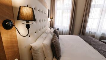 A hotel room with a large bed, a wall-mounted lamp, and a window with curtains.