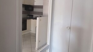 A kitchen with white cabinets, a microwave, and a refrigerator. - Charming City-Center Apartment with Modern Amenities and Nearby Attractions (Bar-le-Duc)