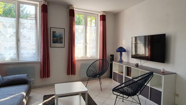 A modern living room with a sofa, a coffee table, a TV, and a bookshelf. - Charming City-Center Apartment with Modern Amenities and Nearby Attractions (Bar-le-Duc)