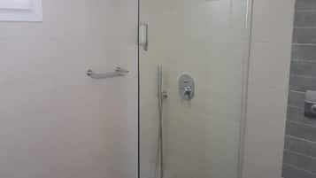 Un baño moderno con ducha de vidrio, inodoro y perchero para toallas.