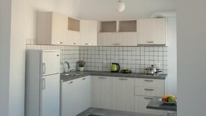 Una cocina moderna con armarios blancos, encimera de mármol y horno empotrado.