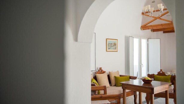 Un área de comedor con una mesa y sillas de madera, un sofá con cojines, y un cuadro en la pared.
