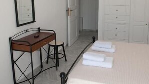 Un dormitorio con cama, escritorio, silla, espejo y armario.