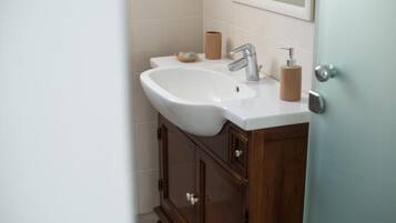 Un baño con un lavamanos blanco, un armario de madera y un espejo sobre el lavamanos.