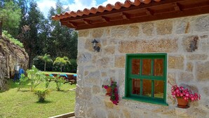 A stone building with a green window and two wall-mounted lanterns.