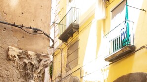 A narrow cobblestone street with a parked scooter, an arched doorway, and a wooden door. - Tasso Apartment - between History and the Coast - (Salerno)