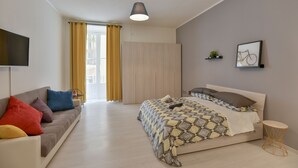 A modern bedroom with a bed, a sofa, a TV, and a small table. - Tasso Apartment - between History and the Coast - (Salerno)