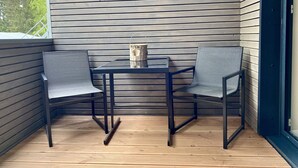 Eine Sitzecke mit zwei Sesseln und einem Tisch, Holzboden und eine Wand mit horizontalen Holzpaneelen.