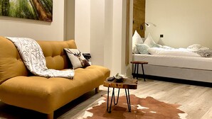 Ein modernes Wohnzimmer mit einer Couch, einem kleinen Tisch und einem Bett.