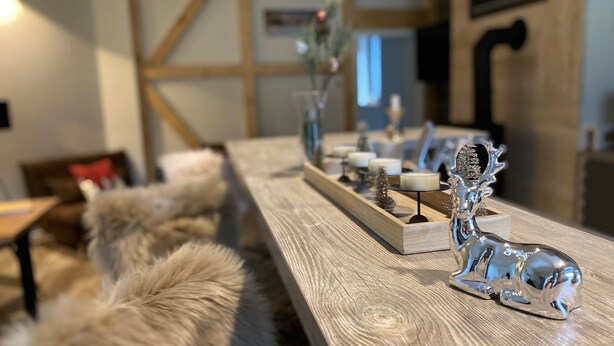Una mesa de madera con elementos decorativos, incluyendo una figura de reno de plata y velas.