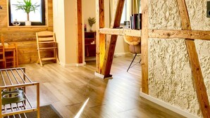 A modern interior with wooden beams, a large window with a plant, and a wooden floor. - App. 4 - wohlBleben (4 Zi, 6 Pers.) (Braunlage)