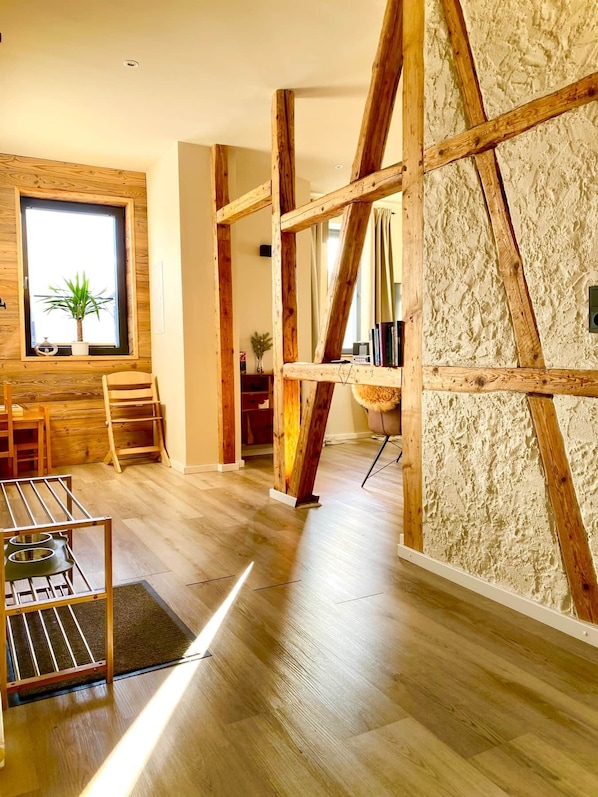 A modern interior with wooden beams, a large window with a plant, and a wooden floor.