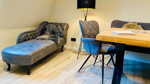 A cozy living area with a tufted sofa, a blue armchair, and a wooden table.