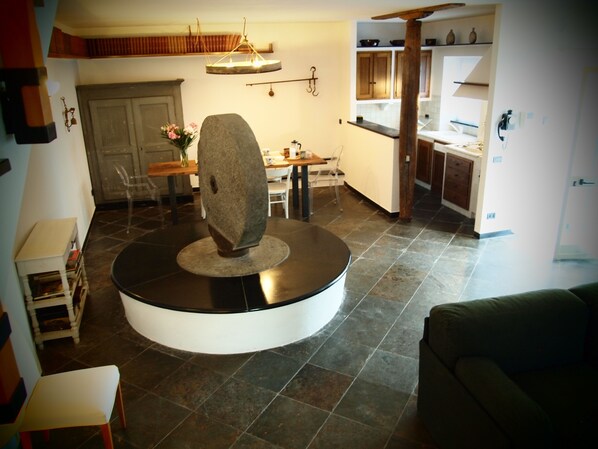 Ein modernes Wohnzimmer mit einem runden Couchtisch in Schwarzweiß, einer Steinskulptur und einem Essbereich mit Holztisch und Stühlen.