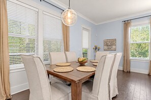 A dining area with a wooden table, beige chairs, and a hanging light fixture. - Blue Haven by the Sea - 3BR/2.5BA Blue Mountain Beach - Sleeps 8 - Community Pool (Santa Rosa Beach)