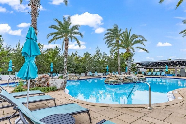A swimming pool with lounge chairs and umbrellas, surrounded by palm trees and a clear sky. - Blue Haven by the Sea - 3BR/2.5BA Blue Mountain Beach - Sleeps 8 - Community Pool (Santa Rosa Beach)