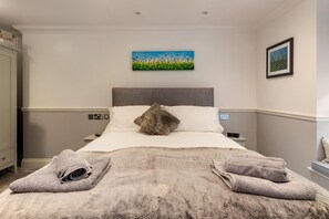 Een hotelkamer met een bed, twee kussens, een pluizig vloerkleed en twee handdoeken.