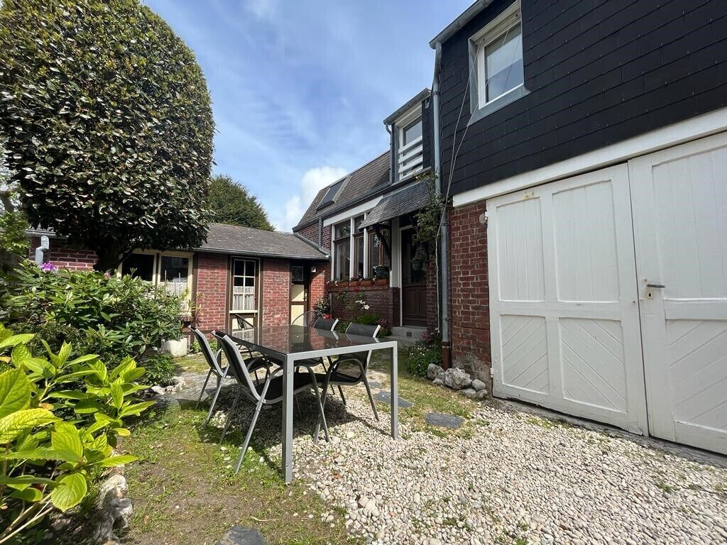 A residential property with a garage, a dining area with a table and chairs, and a well-maintained garden.