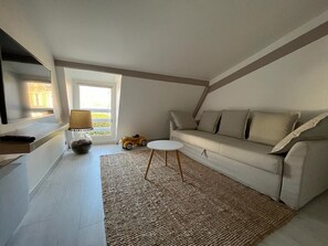 A modern living room with a white sofa, a small round table, and a rug.