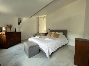 A bedroom with a bed, a dresser, a nightstand, and a mirror.