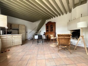 A spacious living area with a kitchen, dining table, chairs, and a fireplace.