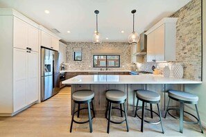 A modern kitchen with a large island, bar stools, and pendant lighting. - Ocean Views - Jacuzzi - Rooftop Deck-walk to beach (San Diego)