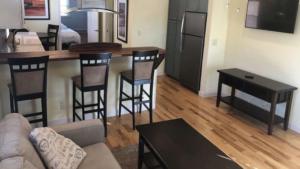 A modern kitchen with dark cabinets, a stainless steel refrigerator, and a bar area with bar stools.
