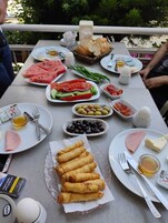 Una mesa dispuesta con diferentes platos, incluyendo sandía, aceitunas y pan, que sugiere un montaje para una comida al aire libre.