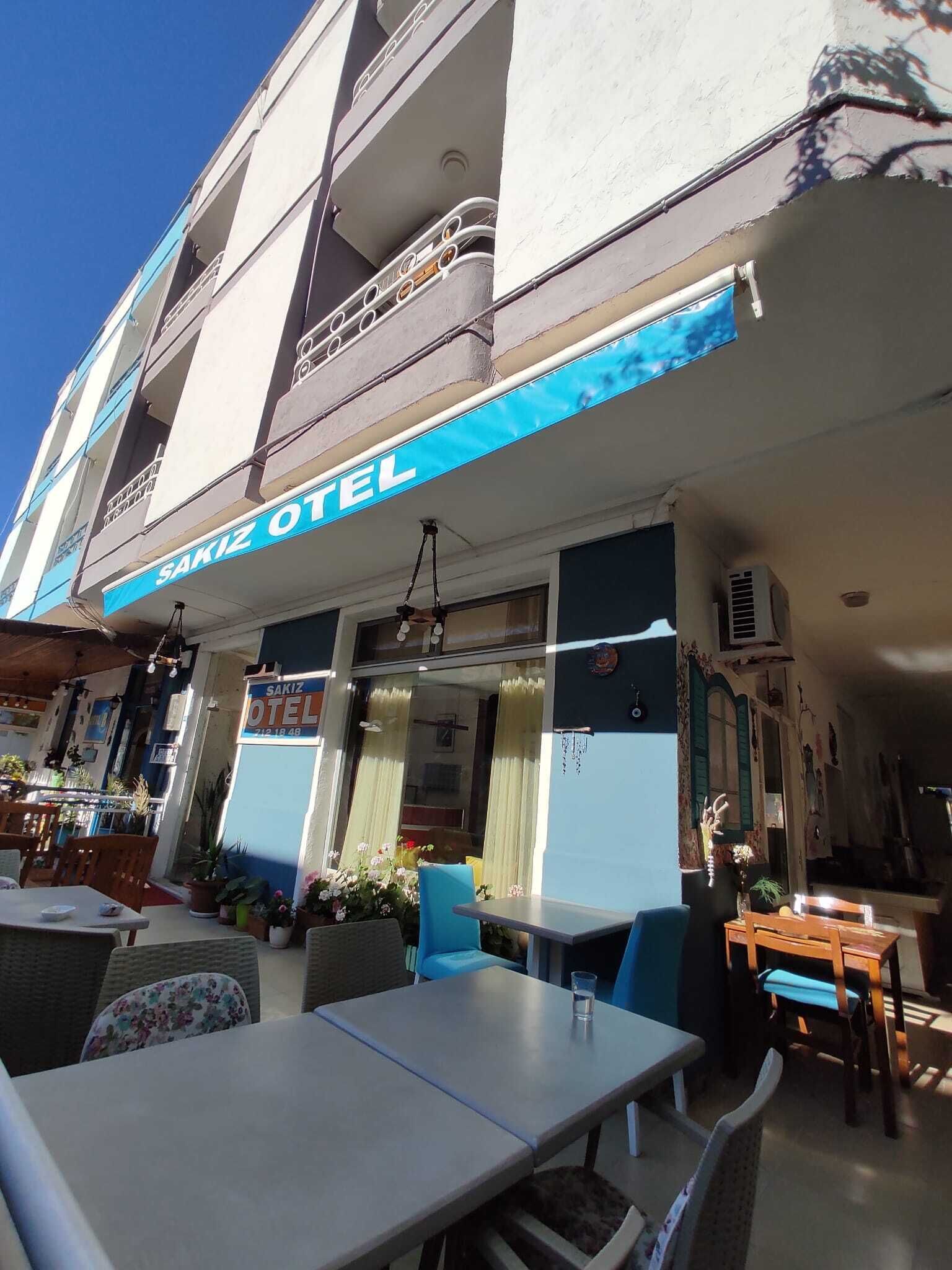 The exterior of Sakiz Hotel with outdoor seating and a blue awning.