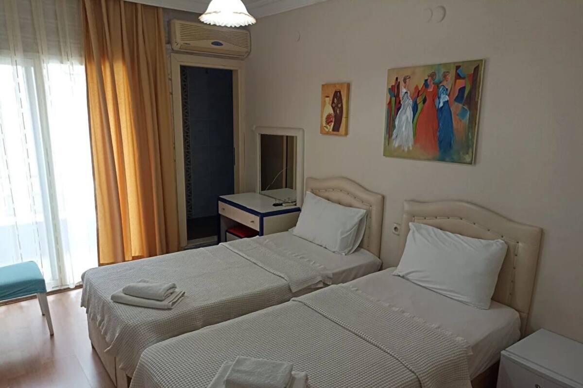 Habitación de hotel con dos camas, un escritorio, una silla, un calefactor y un cuadro en la pared.