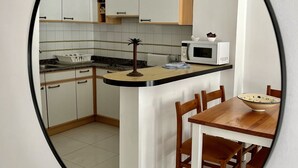 Une cuisine avec des meubles blancs, un four à micro-ondes et une table à manger en bois avec des chaises.