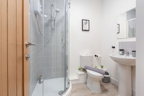 Un baño moderno con cabina de ducha de vidrio, inodoro y lavamanos.