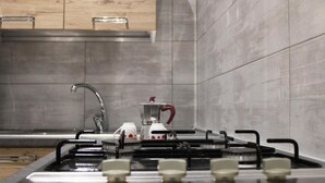 A modern kitchen with a gas stove, stainless steel sink, and wooden cabinets. - Superior Suite (Trapani)