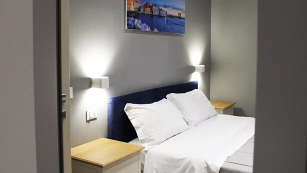 A hotel room with a bed, bedside tables, and a painting on the wall. - Superior Suite (Trapani)