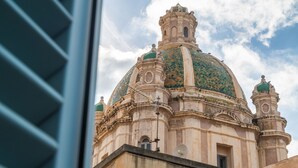 Un edificio histórico con una cúpula grande y dos cúpulas más pequeñas, con detalles arquitectónicos intrincados y una antena parabólica.