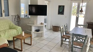 Un salon avec un téléviseur, un canapé, une table et des chaises.