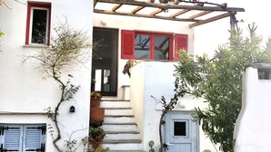 Un bâtiment blanc avec une pergola en bois, un escalier et des plantes en pot.