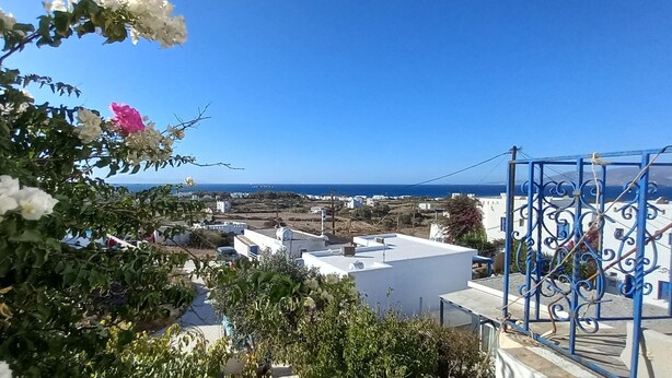 Une ville côtière aux bâtiments blancs, sous un ciel d’un bleu limpide, offrant une vue sur la mer.