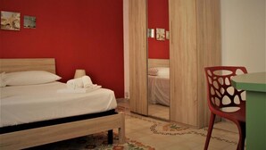 Une chambre à coucher avec un lit, une chaise, une table et un miroir.
