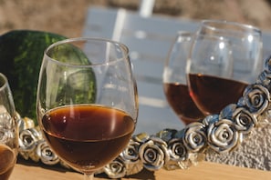 Un verre de vin rouge sur une table, avec des roses en métal décoratives et un fruit vert.