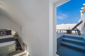 Une chambre à coucher avec un lit, une table de chevet et une vue sur le balcon extérieur.
