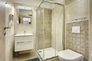 A modern bathroom with a glass-enclosed shower, a white sink, and a toilet. - D&A Central Luxury Apartments (Pula)
