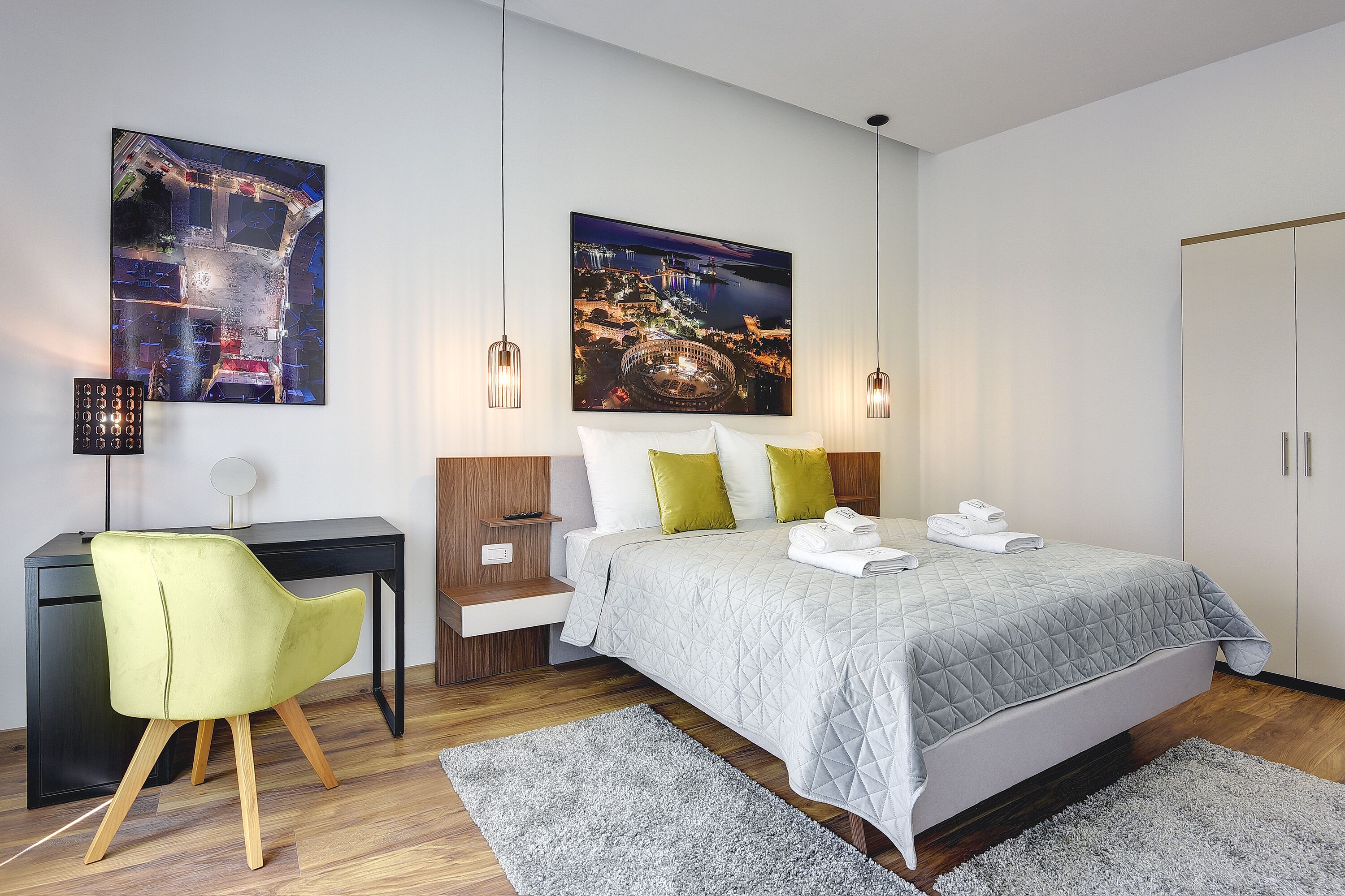 Une chambre à coucher moderne avec un lit, un bureau et deux tableaux accrochés au mur.