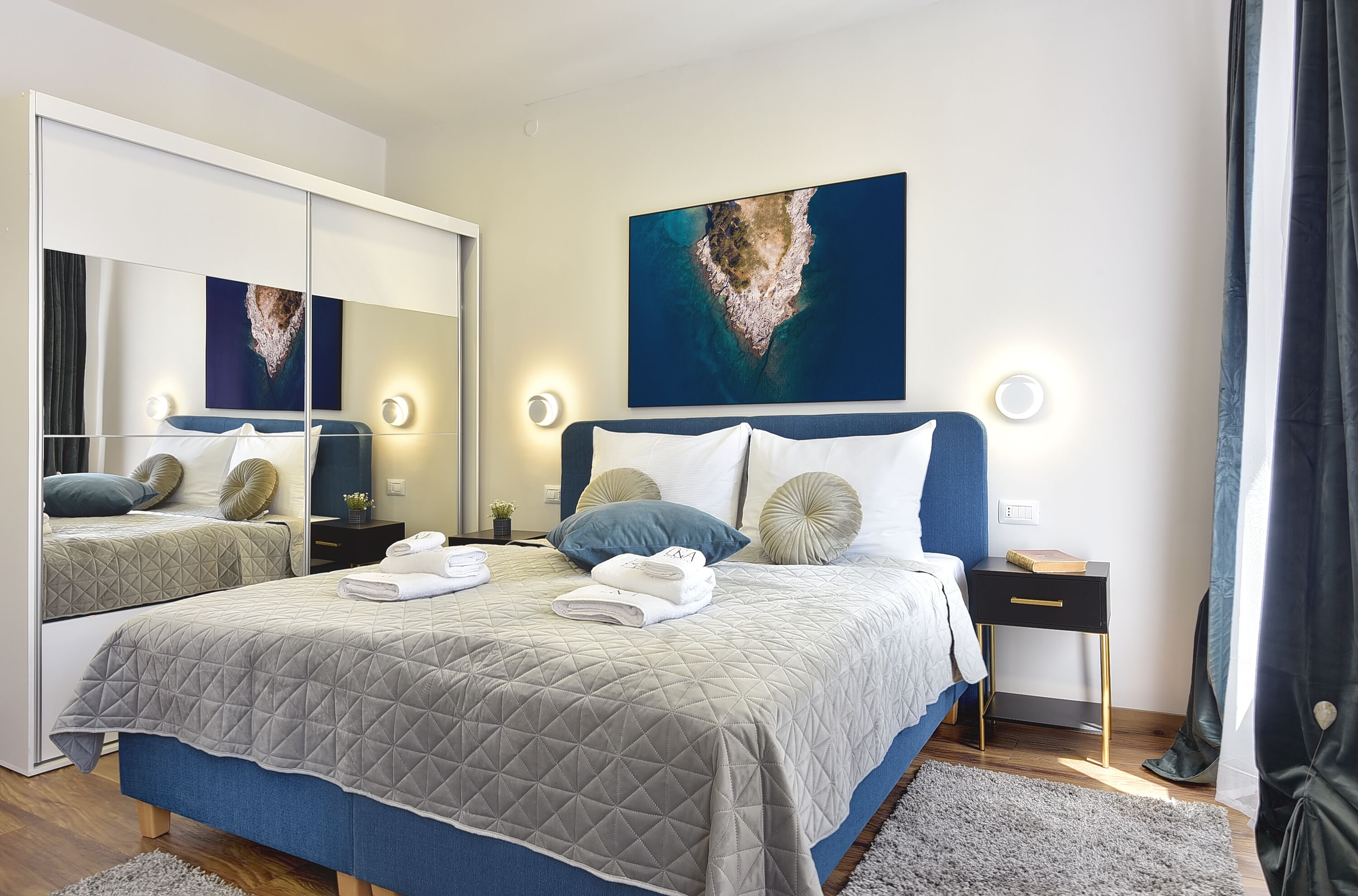 Een moderne slaapkamer met een groot bed, een spiegel en een schilderij van een eiland.