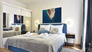 Een moderne slaapkamer met een groot bed, een spiegel en een schilderij van een eiland.