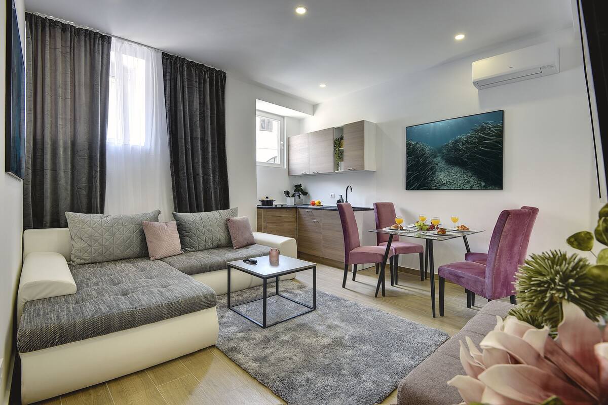 A modern living room with a sofa, coffee table, and dining area with chairs.