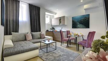 Una sala de estar moderna con sofá, mesa de centro y comedor con sillas.
