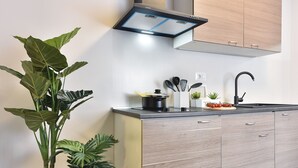 Una cocina moderna con armarios de madera, un grifo negro y una planta en maceta.