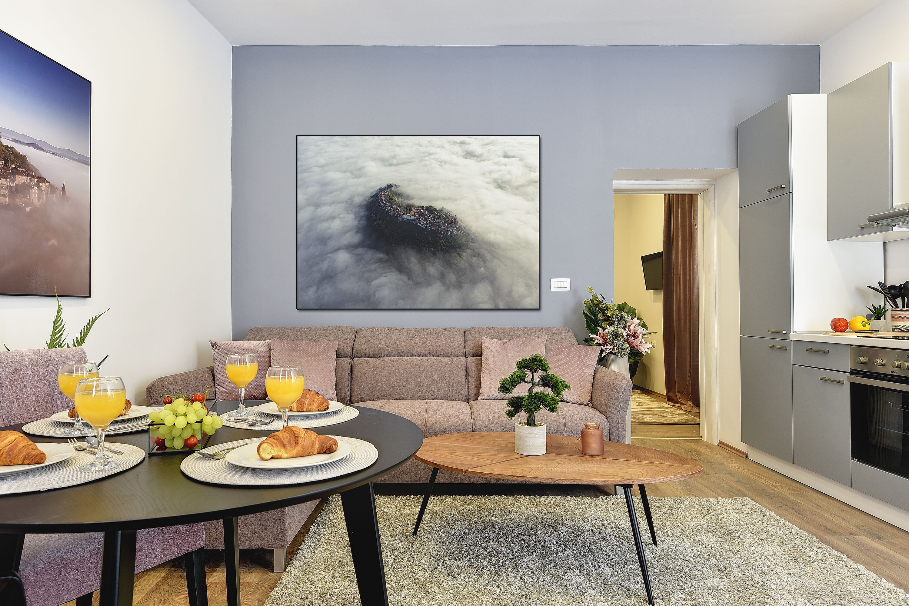 A modern living room with a sofa, coffee table, and dining area set with breakfast items.